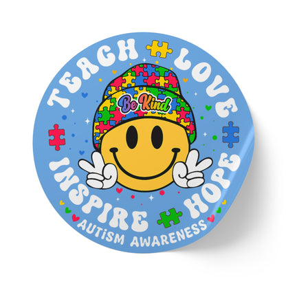 Autism awareness round sticker roll with smiley puzzle piece design and "Teach Love Inspire Hope" message on paper labels.