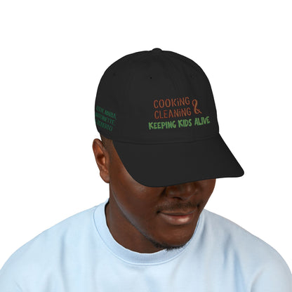 Organic baseball cap with embroidered custom name, featuring a humorous "cooking, cleaning & keeping kids alive" message on a casual hat.